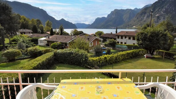 Ein Balkon mit Tisch und Stühlen mit Blick auf eine Berglandschaft und einen See.