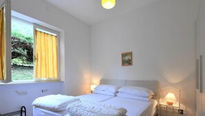 Ein Schlafzimmer mit einem großen Bett, zwei Nachttischlampen, einem Fenster mit Vorhängen und einem kleinen Bild an der Wand.