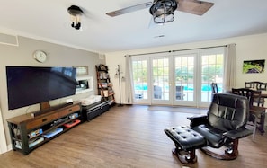 A spacious living room with a flat-screen TV, leather recliner, and a ceiling fan.