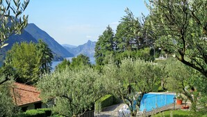 A villa with a swimming pool, surrounded by lush greenery and mountains in the background.
