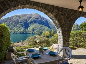 A table set for two with blue plates and glasses, overlooking a lake and mountains. - Lovely apartment for 4 guests with WIFI, pool, TV, terrace and pets allowed (San Mamete)