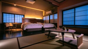 A traditional Japanese-style room with tatami flooring, a low table with a tea set, and a large shoji screen window.