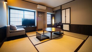 A traditional Japanese-style room with tatami flooring, a low table, a sofa, and sliding doors.
