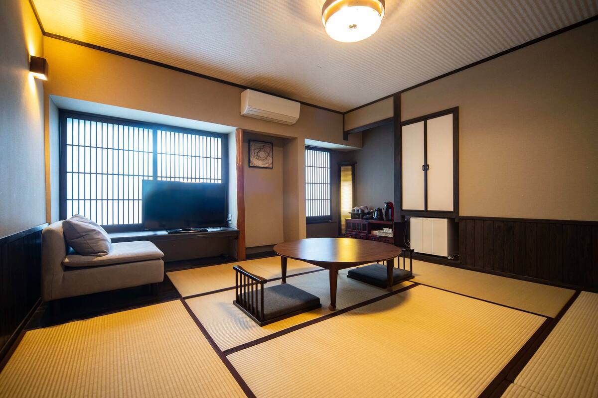 A traditional Japanese-style room with tatami flooring, a low table, a sofa, and sliding doors.