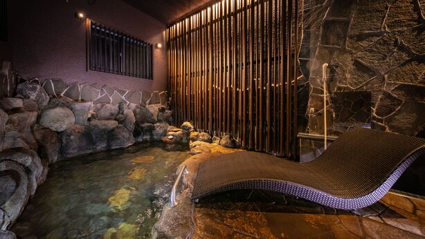 A spa area with a hot tub, stone walls, and a bamboo screen.