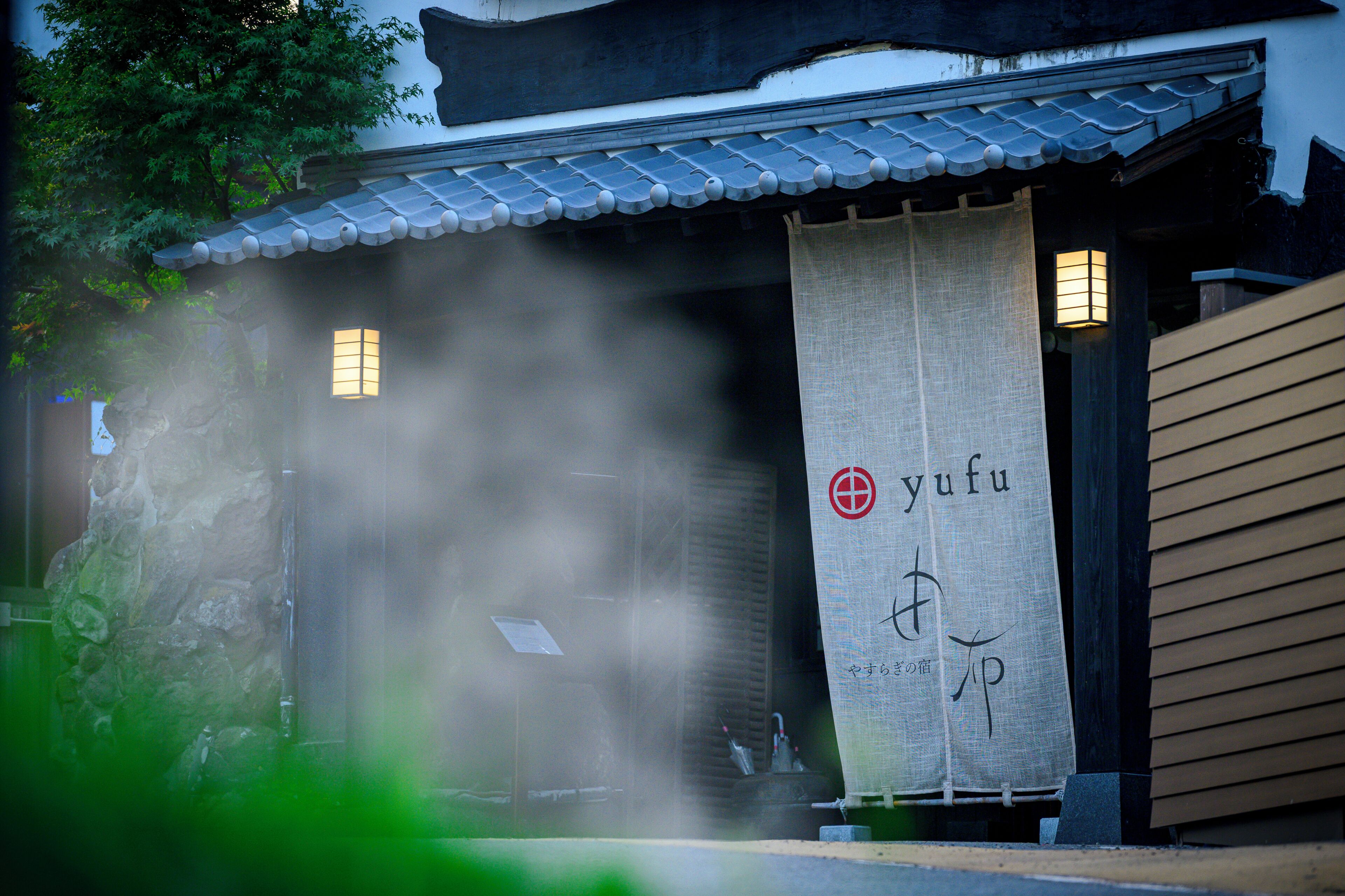 Ein traditionelles japanisches Gebäude mit einem Ziegeldach, einem Banner mit japanischen Schriftzeichen und einer Steinmauer.
