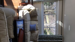 Ein Eckzimmer mit einer gepolsterten Sitzecke, einem Fenster mit Blick auf Bäume und einer Heizung.