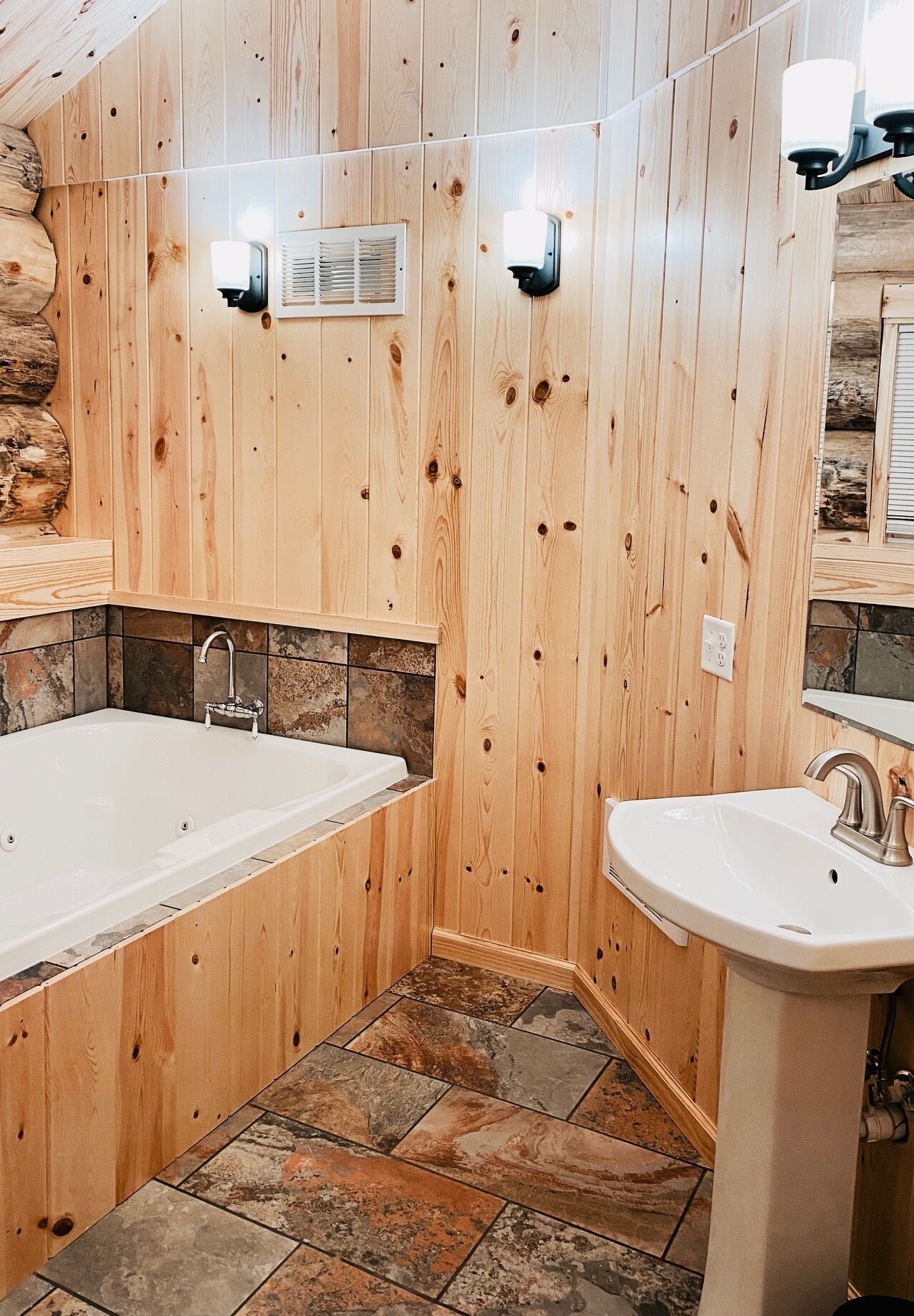 Un baño con paredes de madera, una bañera, un lavabo y una zona de ducha.