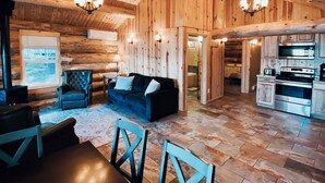 A log cabin interior with a living area, dining space, and kitchen.
