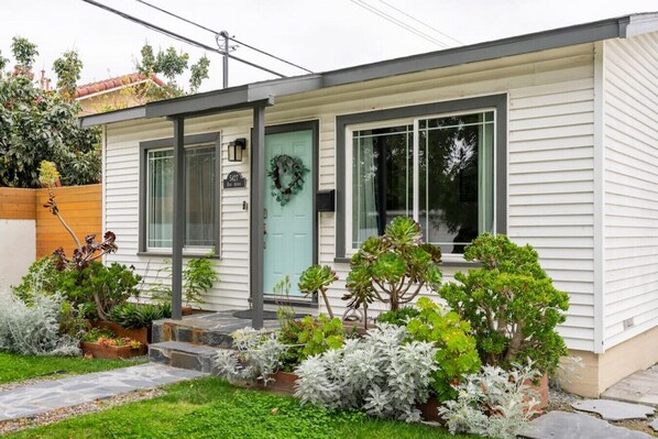 A modern single-story house with a front porch, a mailbox, and a mailbox number sign.