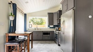Una cocina moderna con un refrigerador de acero inoxidable, gabinetes oscuros y piso de mármol.