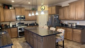 A kitchen with wooden cabinets, a granite countertop, stainless steel appliances, and pendant lighting.