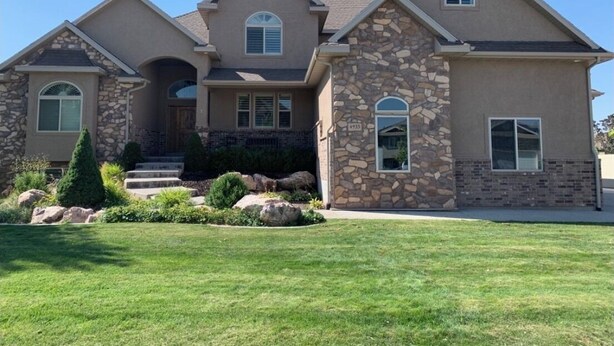A two-story house with a stone facade, a front porch, and a well-maintained lawn.