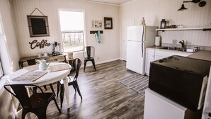 A kitchen with a dining area, wooden flooring, a ceiling fan, and a refrigerator. - Farmhouse right off of I-5 (Tangent)