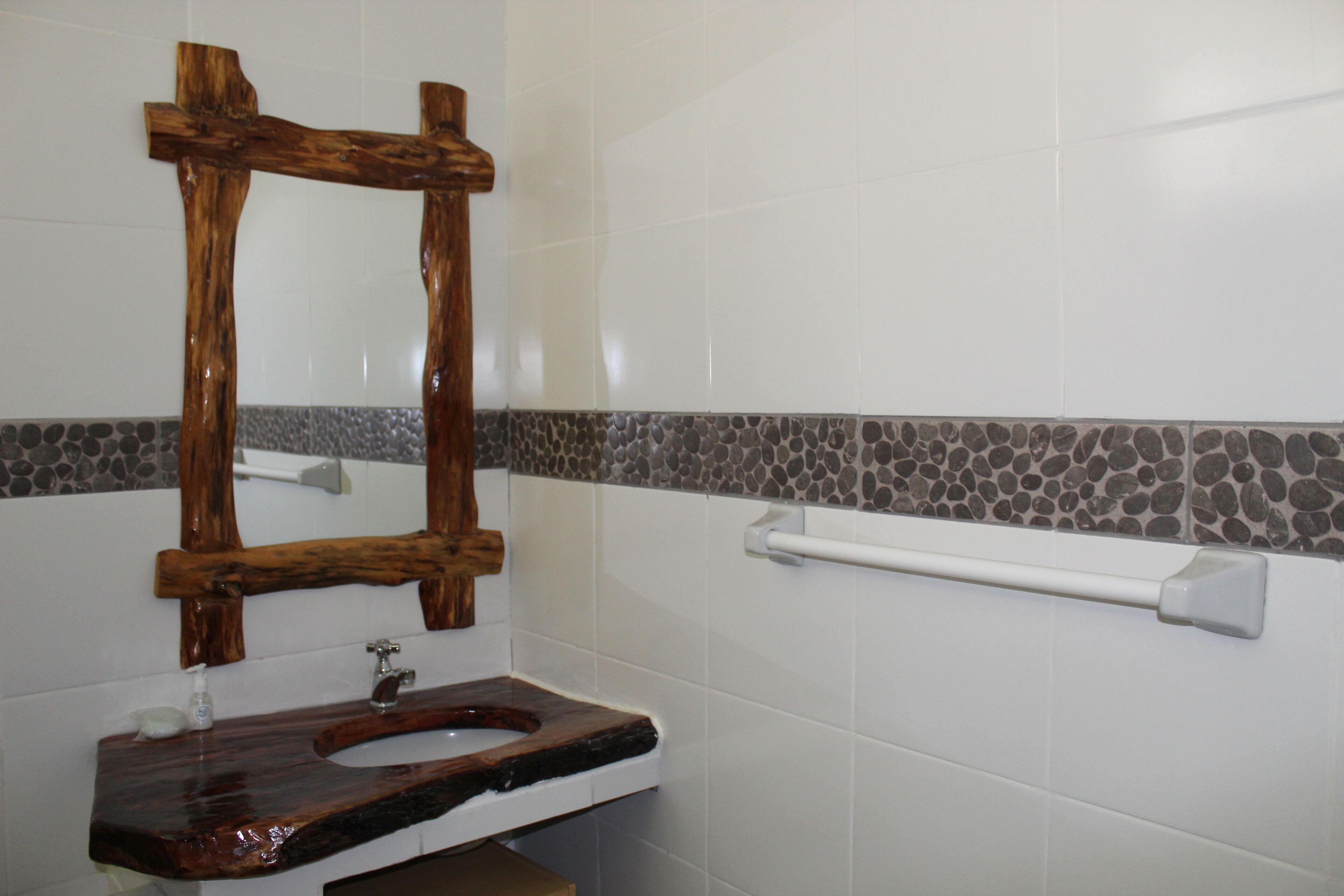 Un bagno con uno specchio con cornice in legno, un lavabo in marmo e un portasciugamani.