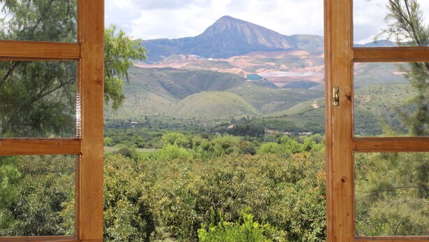 Une vue à travers une fenêtre à cadre en bois, donnant sur un paysage montagneux avec un sommet particulièrement imposant.