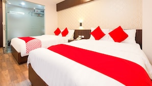 Une chambre d’hôtel avec deux lits, chacun agrémenté de draps rouges et blancs, une table de chevet avec une lampe et un mur décoré d’un motif.