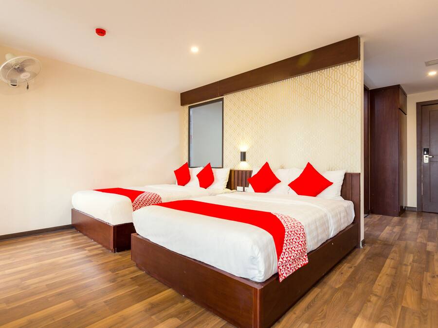 Una habitación de hotel con dos camas, suelo de madera, un espejo grande y una puerta.