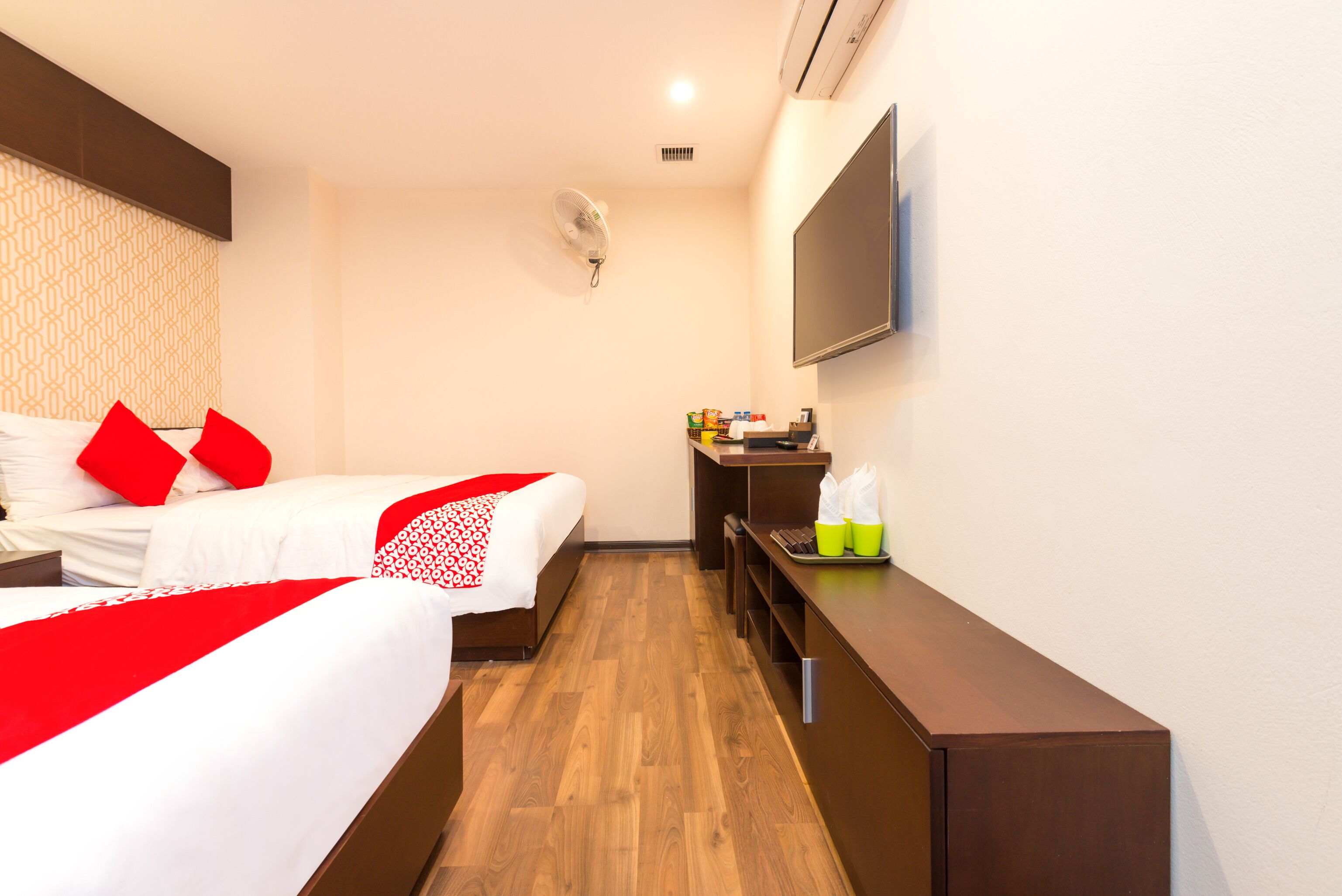 A hotel room with two beds, a desk, a flat-screen TV, and a minibar.