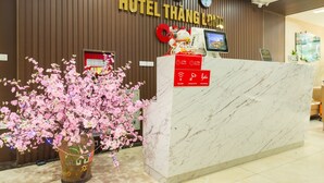 Un comptoir d’accueil d’hôtel avec un revêtement en marbre, un écran numérique et un panneau indiquant que le Wi-Fi est gratuit et que l’enregistrement est possible 24 heures sur 24.