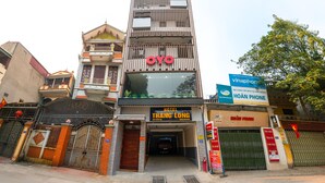 Un immeuble à plusieurs étages, sur lequel on peut voir une enseigne indiquant « OYO Hotel Thanh Long » et une autre indiquant « Hoan Phone ».