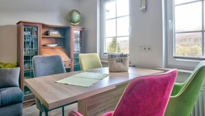 A dining area with a wooden table, colorful chairs, a globe on a shelf, and a window with a view of trees. - Phileas by Interhome (Schwalenberg)