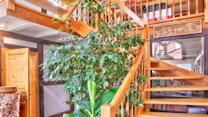A wooden staircase with a large plant in the center, surrounded by bookshelves and a fireplace. - Phileas by Interhome (Schwalenberg)
