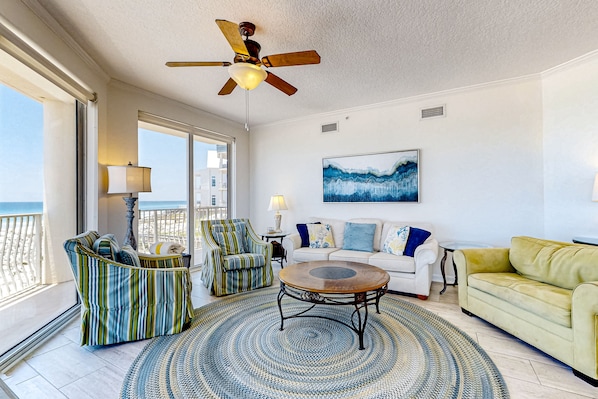 Relax in a spacious living area with a comfortable sofa, striped armchair, and large windows.