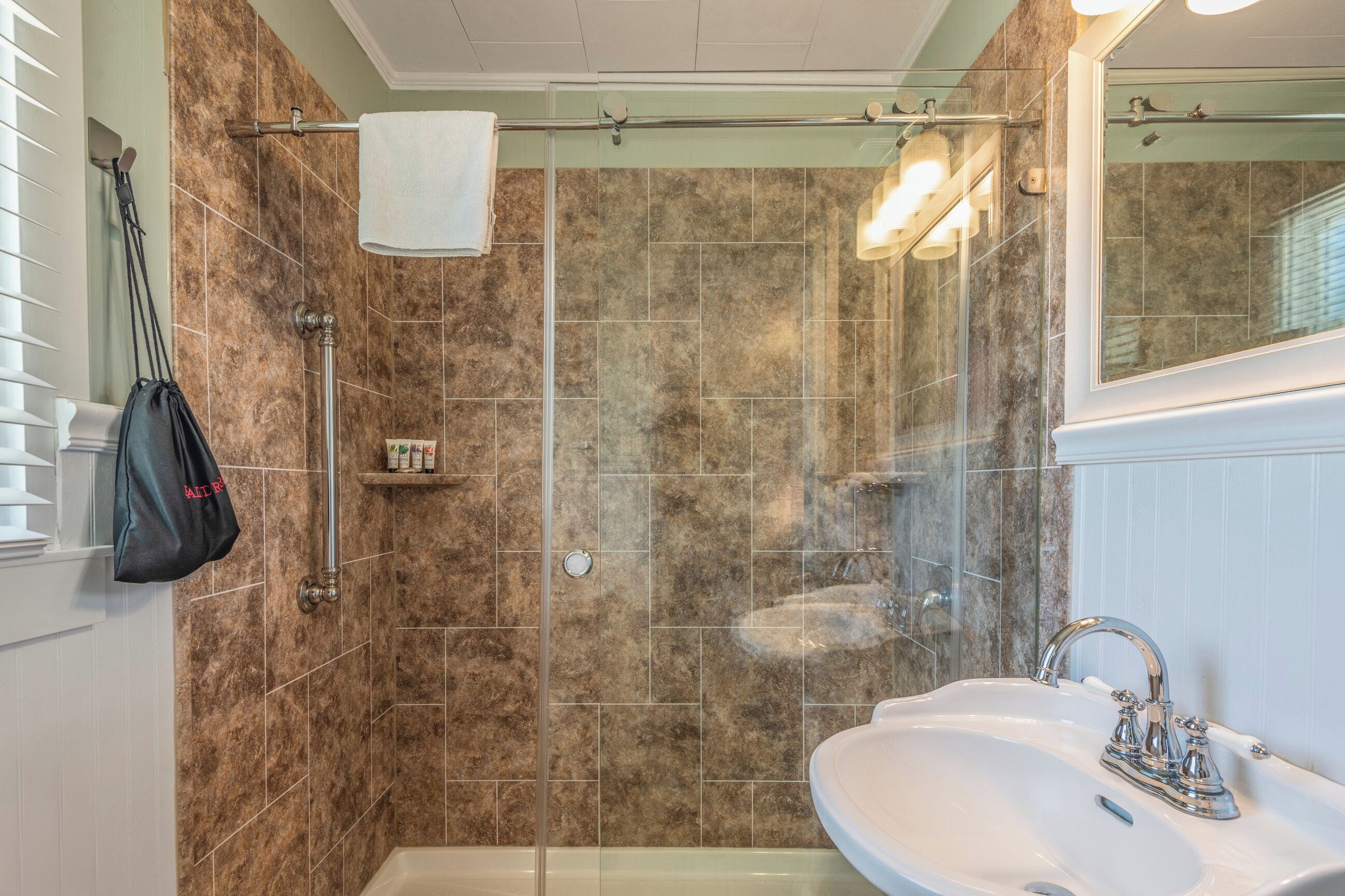 A bathroom with a shower, a sink, and a towel rack.