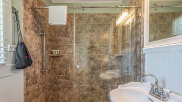 A bathroom with a shower, a sink, and a towel rack.
