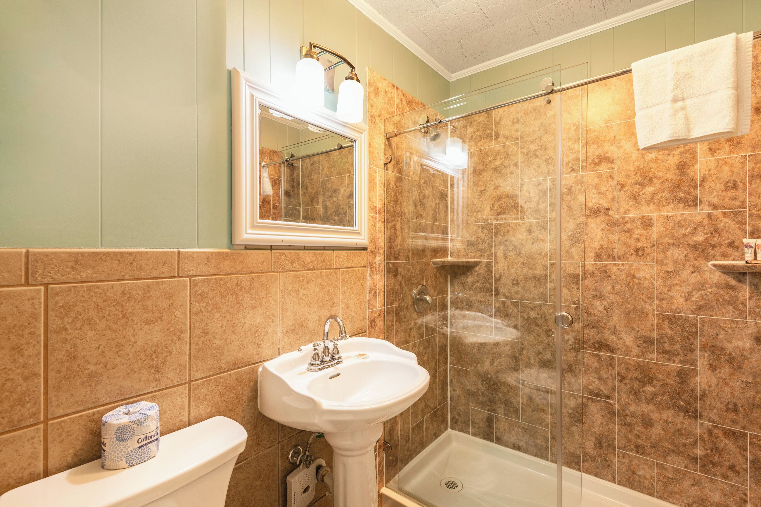 Une salle de bain équipée de toilettes, d’un lavabo et d’une douche à parois de verre.
