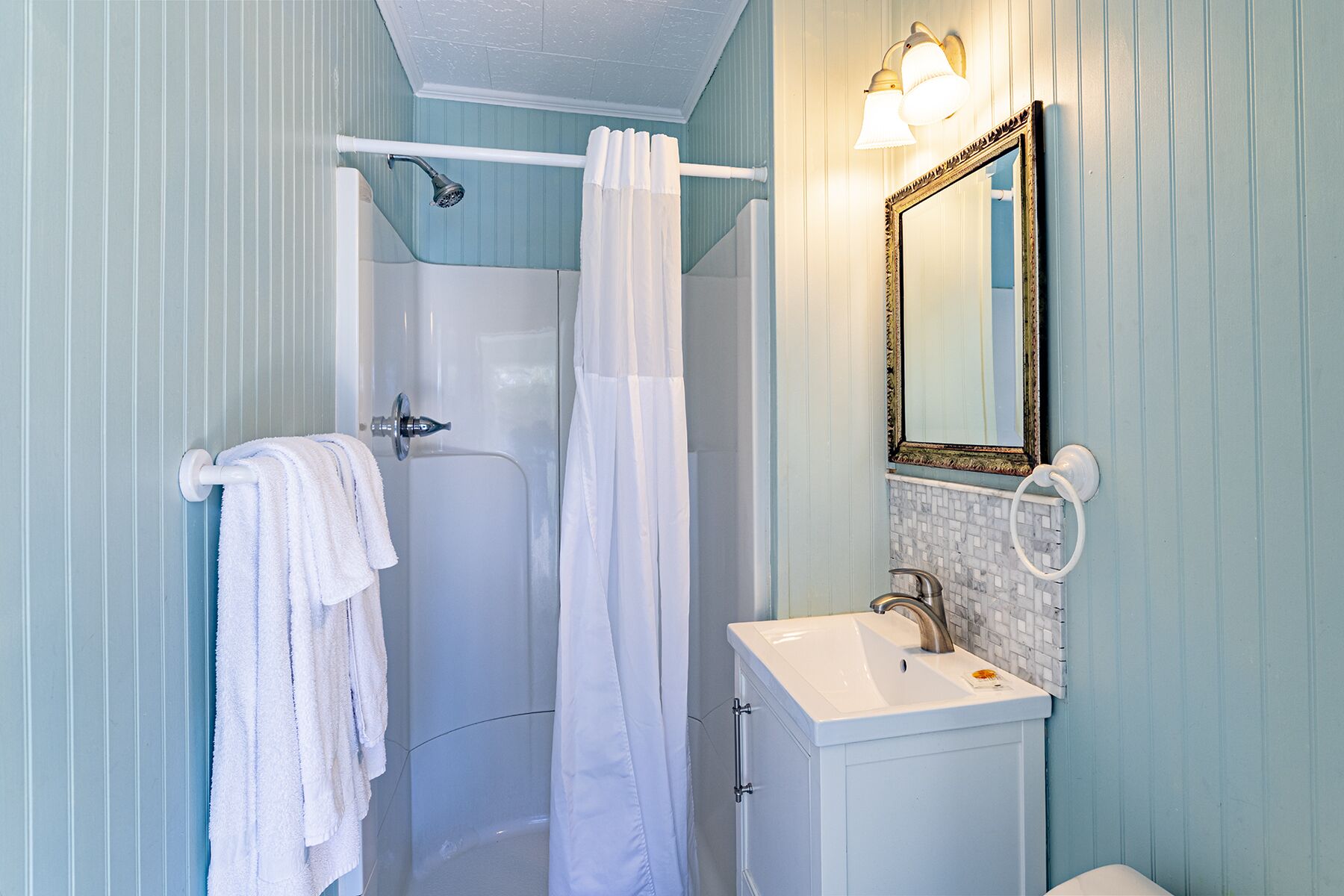 A bathroom with a shower, a sink, and a mirror.