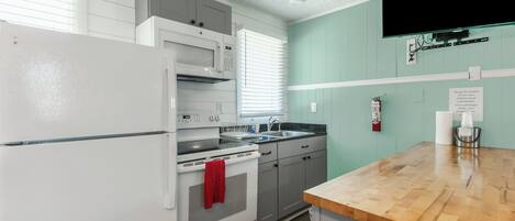 A kitchen with white appliances, a wooden countertop, and a teal wall.