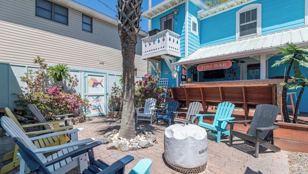 A tiki bar with outdoor seating and a palm tree. - Island Guesthouse and Motel (Manteo)