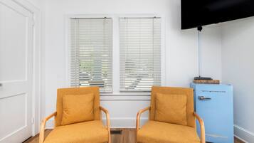 A room with two wooden chairs, a blue cabinet, and a television mounted on the wall.