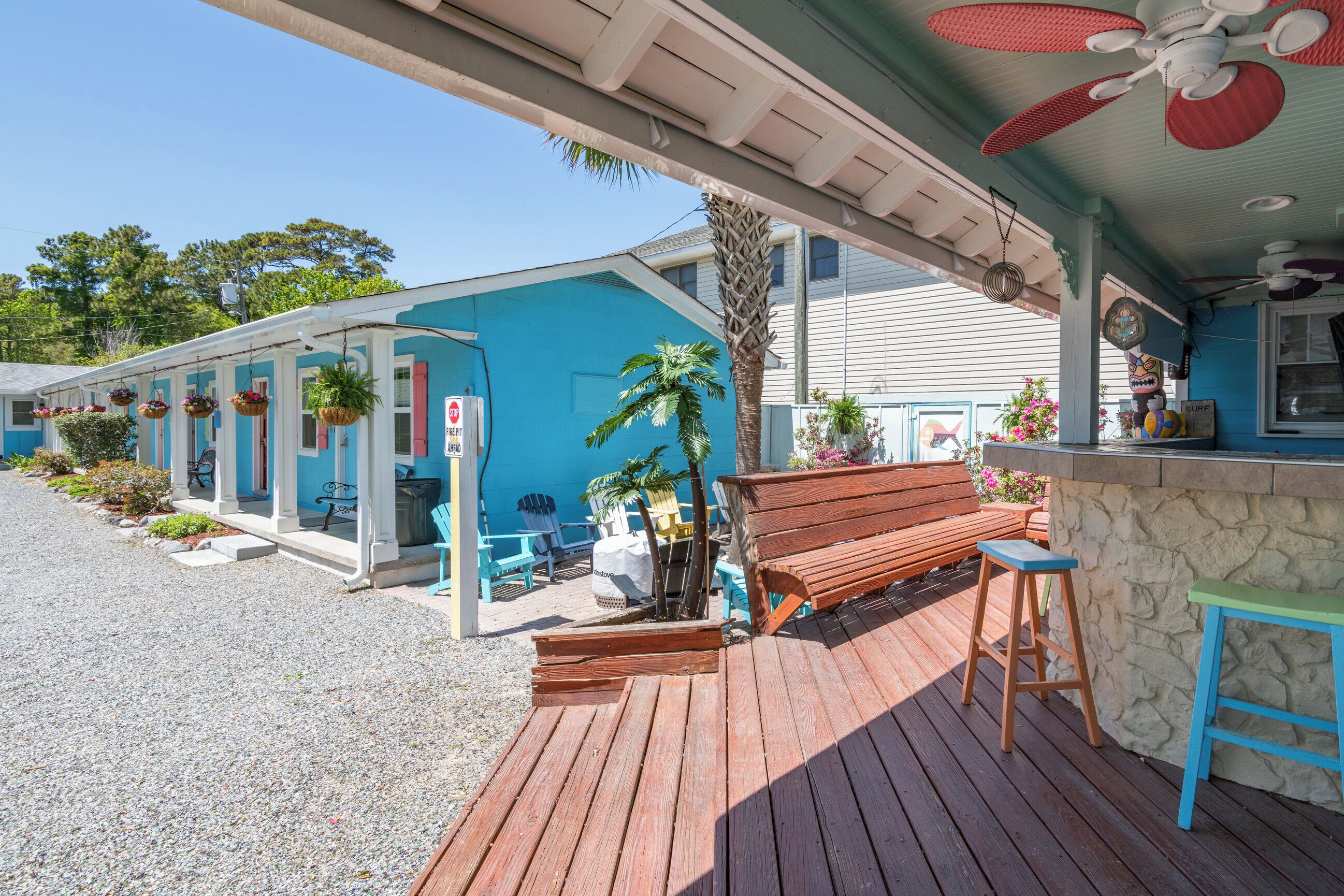 Un espace extérieur abrité doté d’une terrasse en bois, d’un banc et d’un coin bar avec des tabourets.