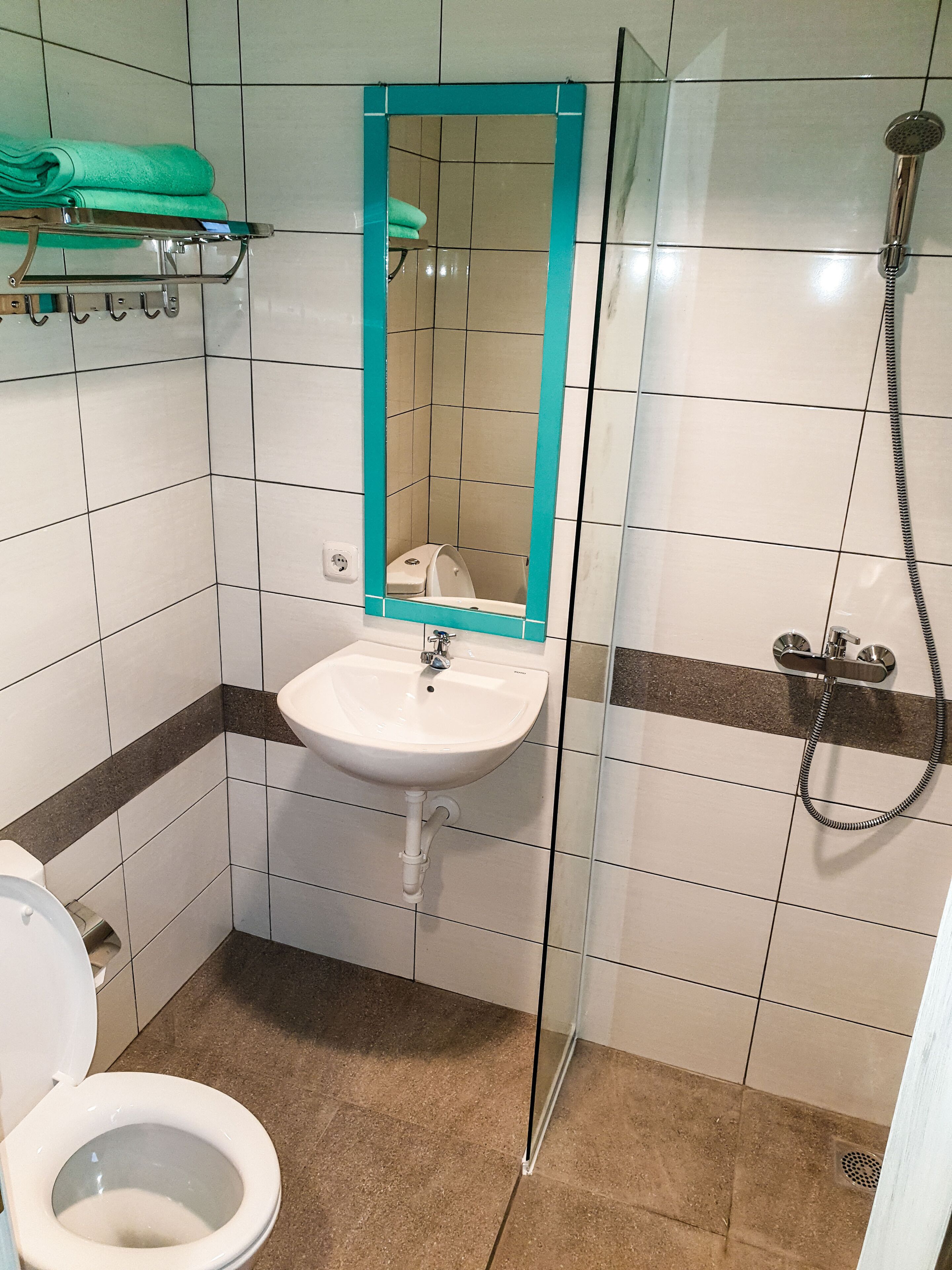 Un baño con lavamanos blanco, espejo, inodoro y ducha.