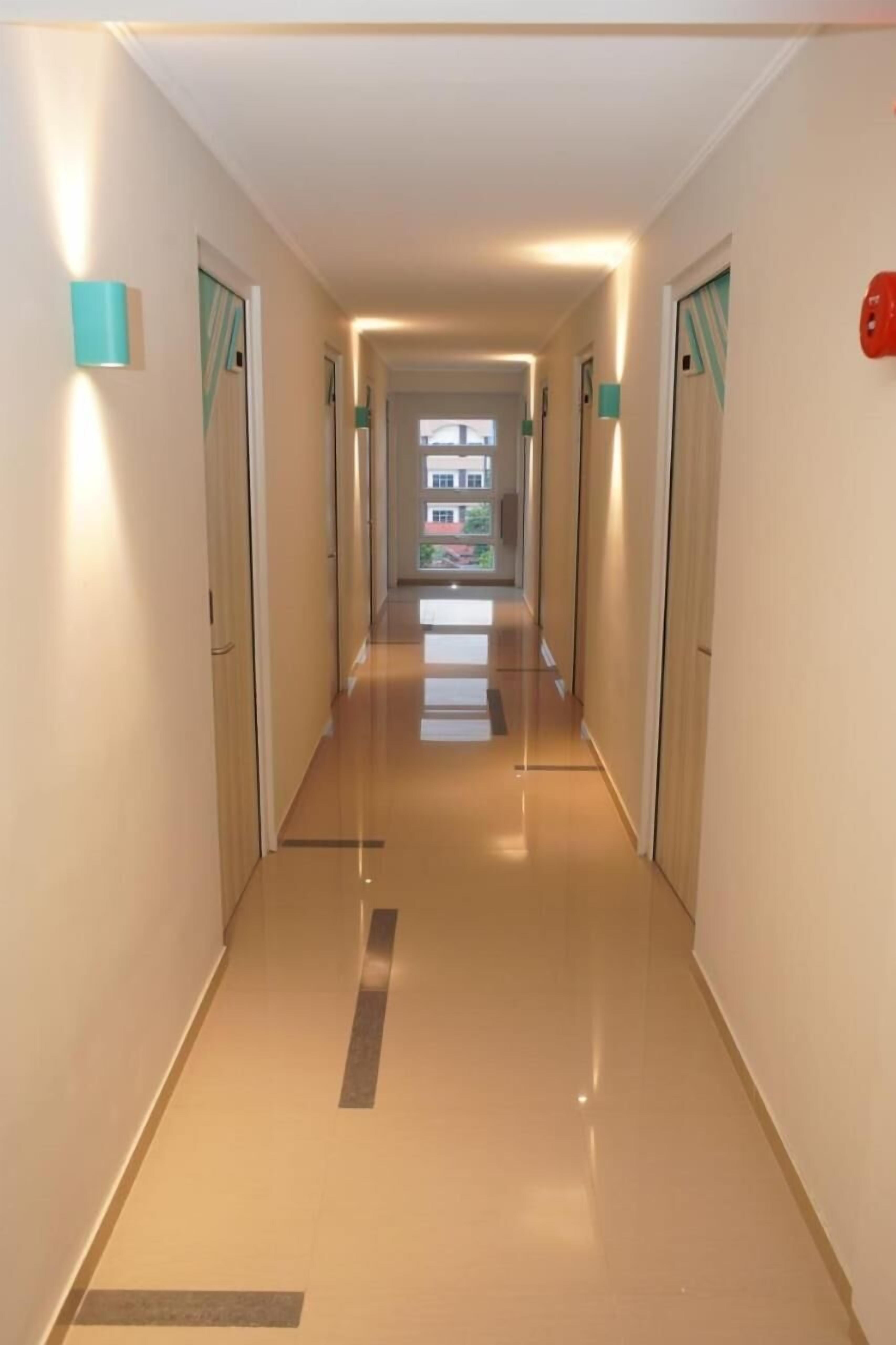 A corridor with a shiny floor, doors on both sides, and a view of a building outside.