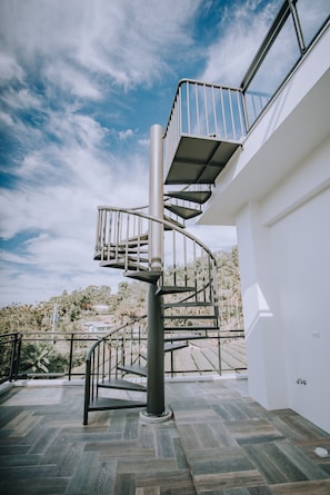 Stunning outdoor staircase leads to a spacious balcony overlooking a serene landscape.