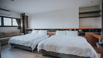 A modern hotel room with two beds, a sofa, a desk, and a large window.