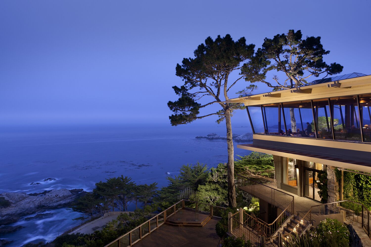 Un bâtiment moderne doté d’un grand balcon en verre donnant sur l’océan.