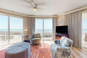 Relax in this inviting living room with a bay window offering a view of the beach, a flat-screen TV, and a comfortable seating area.