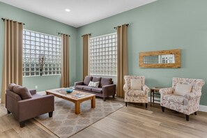 Relax in a comfortable seating area with a sofa and armchairs, surrounded by natural views and elegant decor.