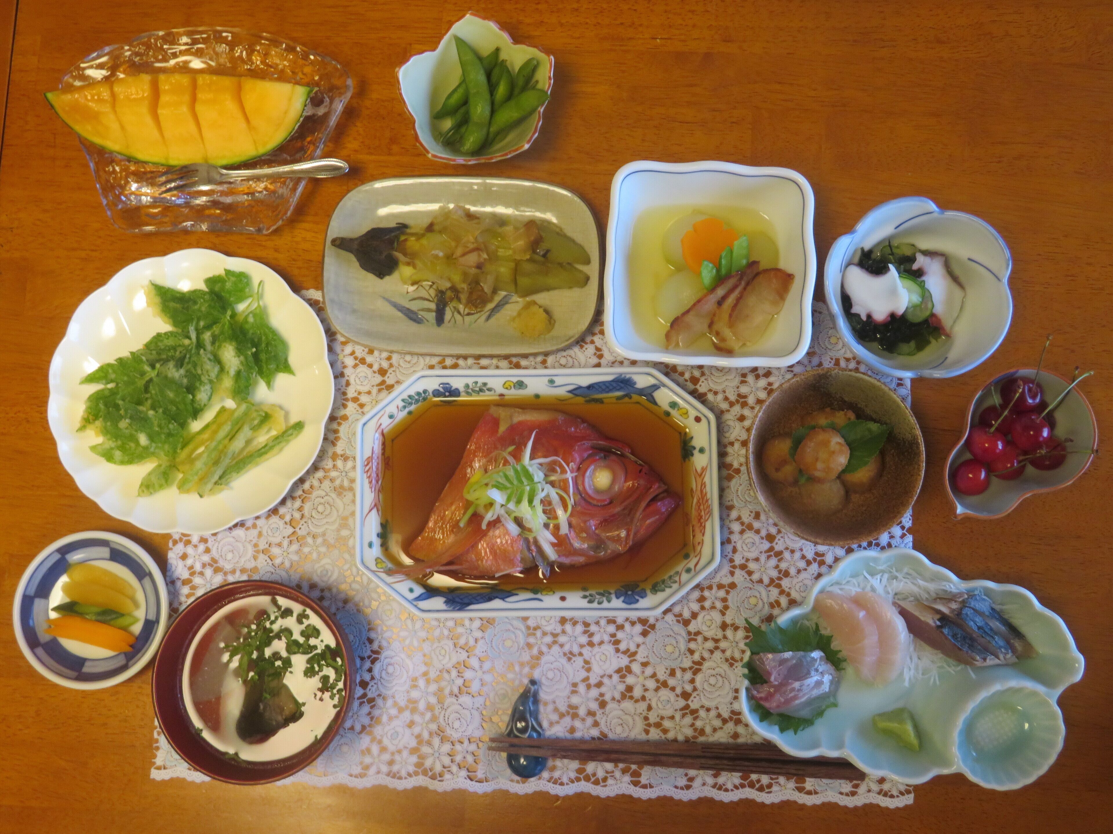Une table garnie de divers plats, notamment du poisson, des légumes et des fruits.