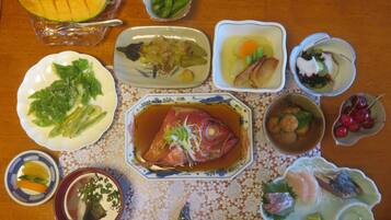 Une table garnie de divers plats, notamment du poisson, des légumes et des fruits.