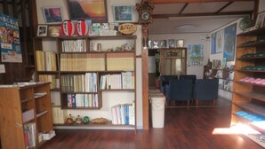 Une bibliothèque avec des étagères en bois, un sol recouvert de moquette et une horloge au mur.