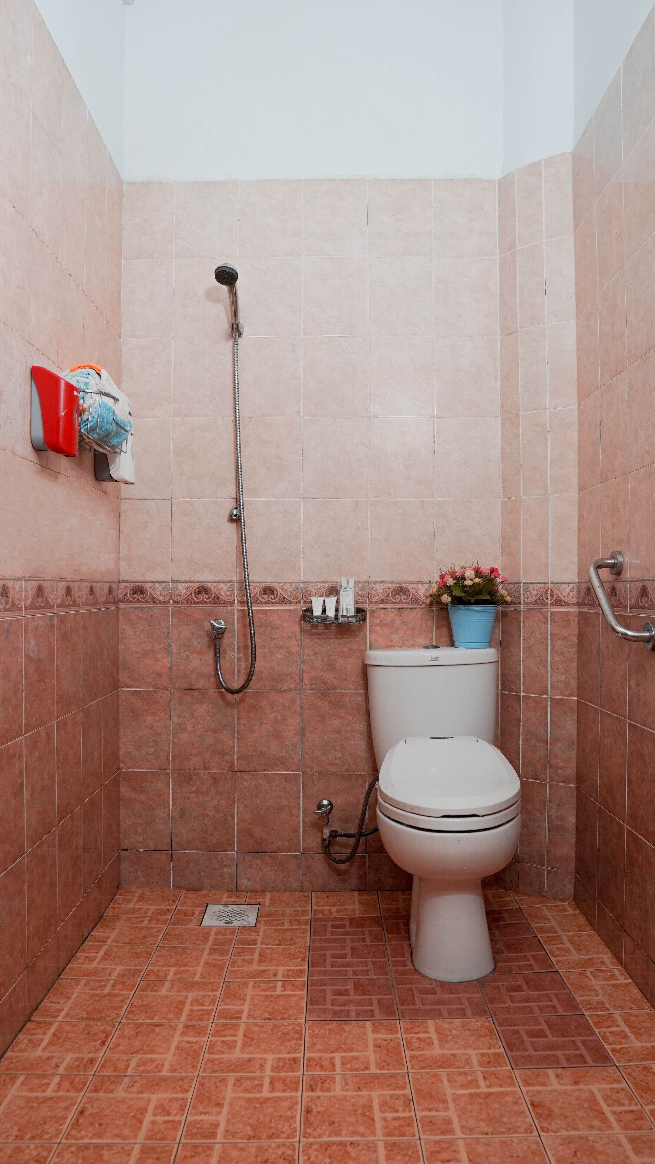Un baño pequeño con ducha, inodoro y un estante con artículos de tocador.