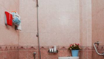 Un baño pequeño con ducha, inodoro y un estante con artículos de tocador.