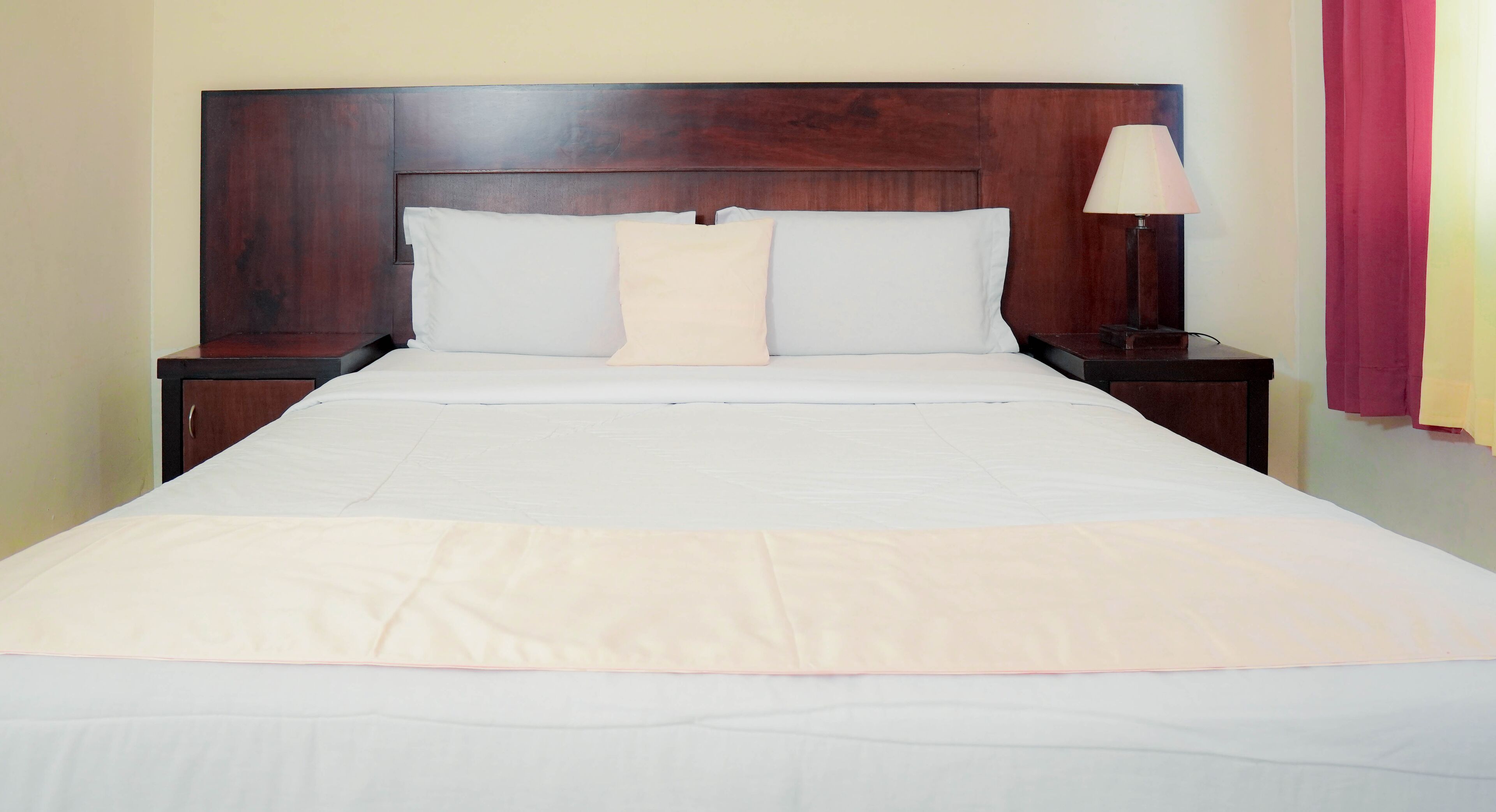 A neatly made bed with white bedding and a wooden headboard.