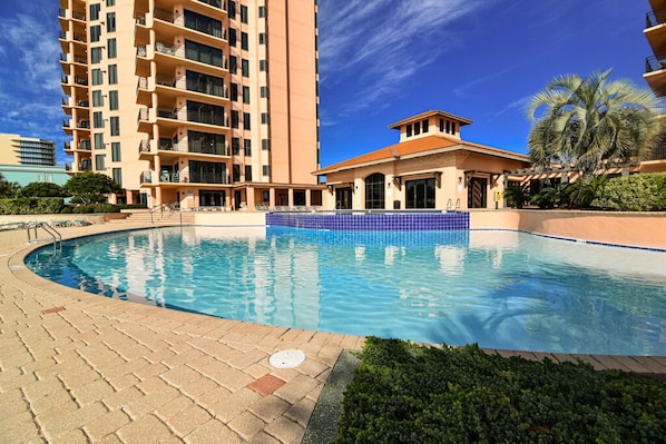 Una piscina con borde de azulejos, rodeada por un paseo de ladrillo.